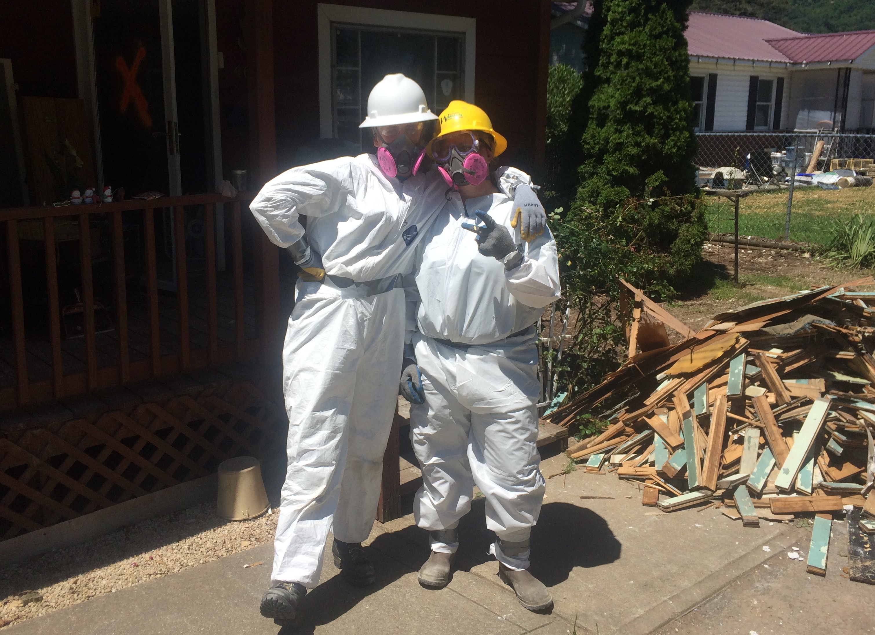 WCC AmeriCorps members stand near pile of debris they removed while mucking and gutting a West Virginia home.